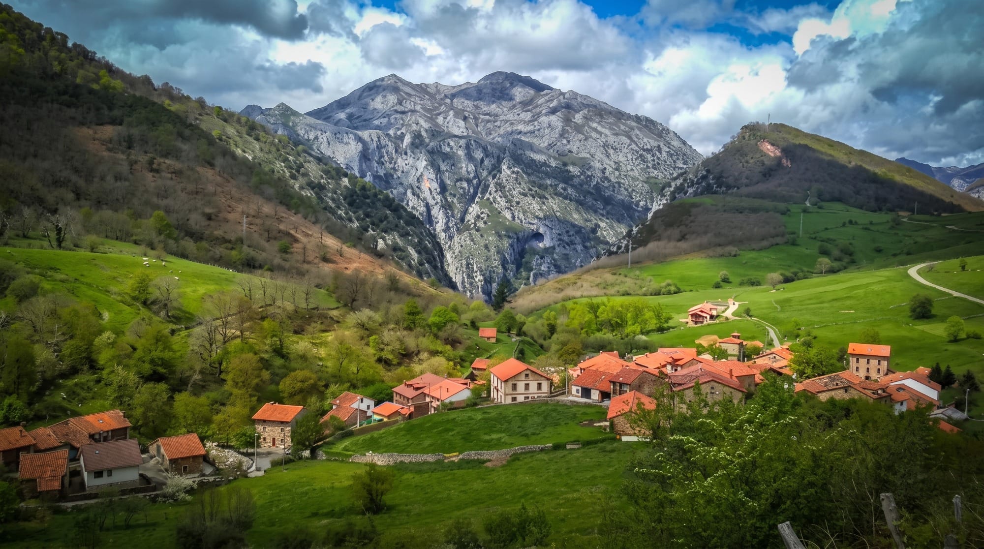 Blick auf das Kloster Santo Toribio de Liébana am Ende des Weges, dahinter die Berge der Picos de Europa