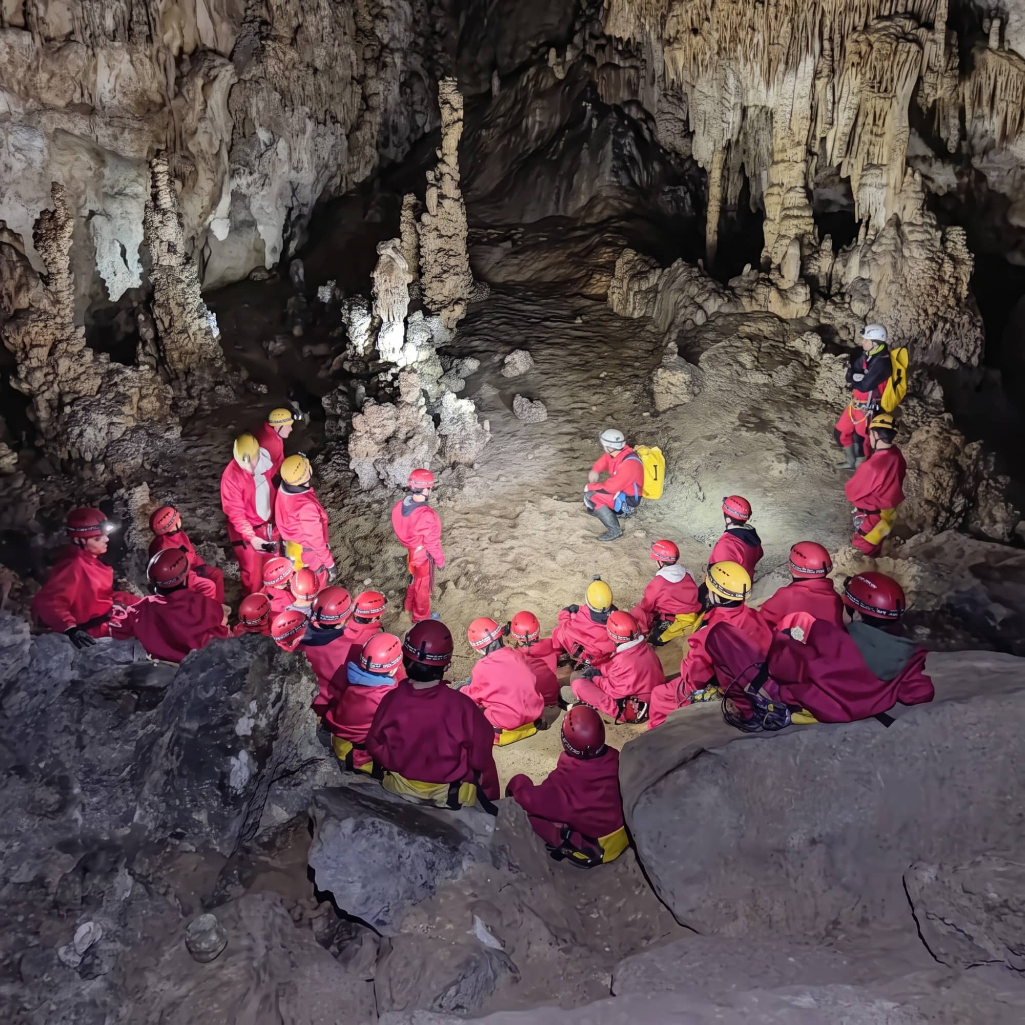 Grupo con casco y frontal reptando por una galería en una cueva del Alto Asón