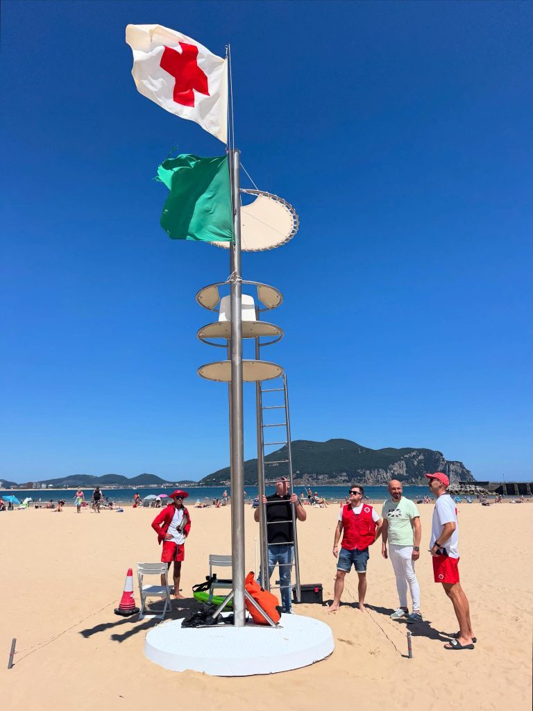 Rettungsschwimmerturm mit gehisster grüner Flagge an einem Strand der kantabrischen Ostküste (Region Noja oder Laredo), an einem Sommermorgen mit noch wenigen Menschen