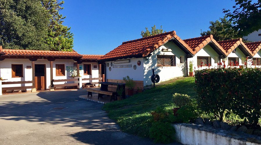 Exterior facade of La Cabaña del Abuelo Peuto, the pilgrim hostel in Güemes, with the wooden cabins in the garden