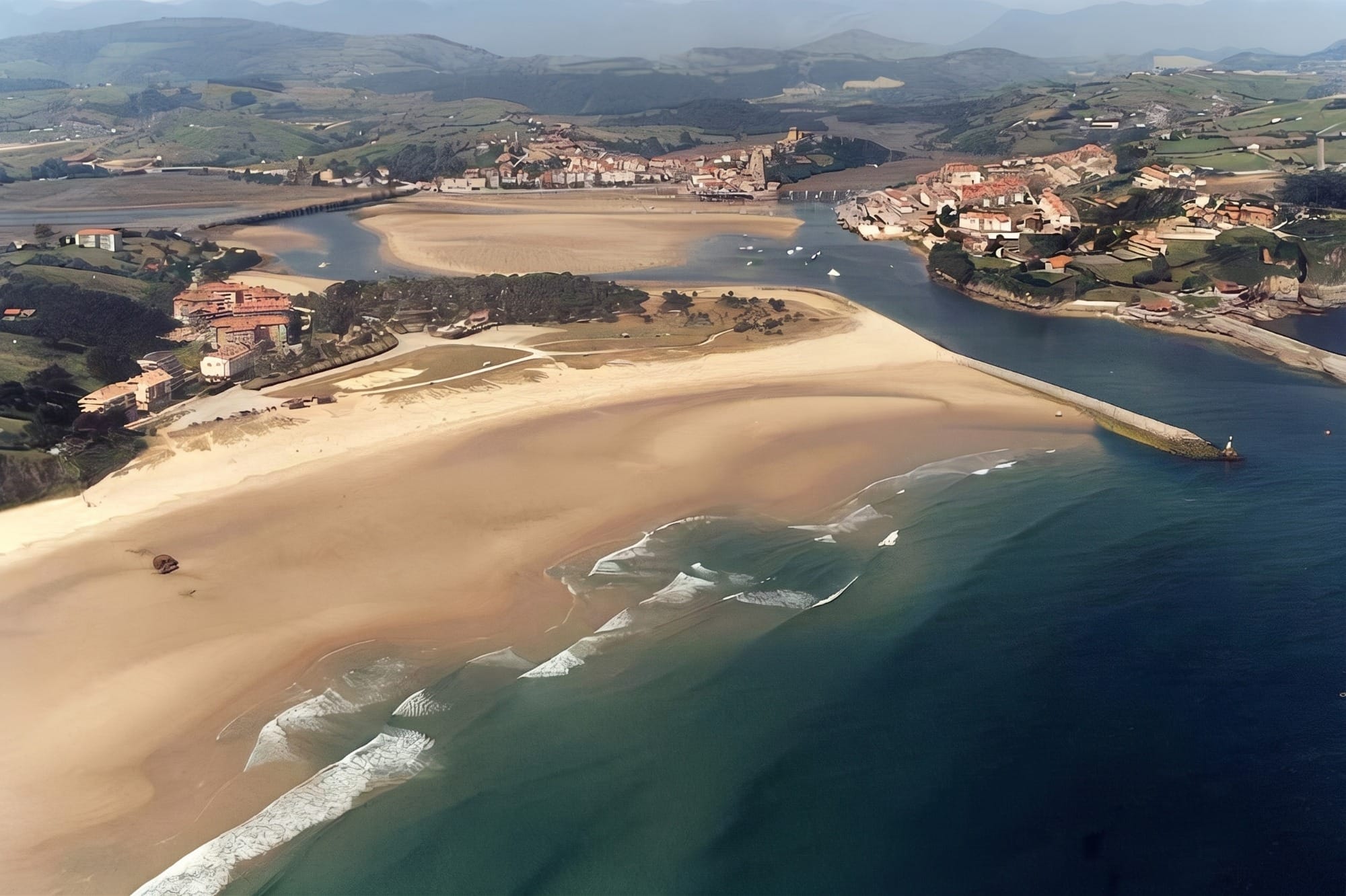 Vista general de la playa de Merón desde la orilla, arena extensa y dunas al fondo, luz de mañana.