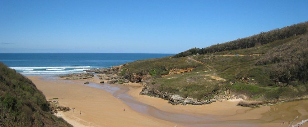 Goldener Sand und niedrige Klippen am Strand von Galizano bei Ebbe