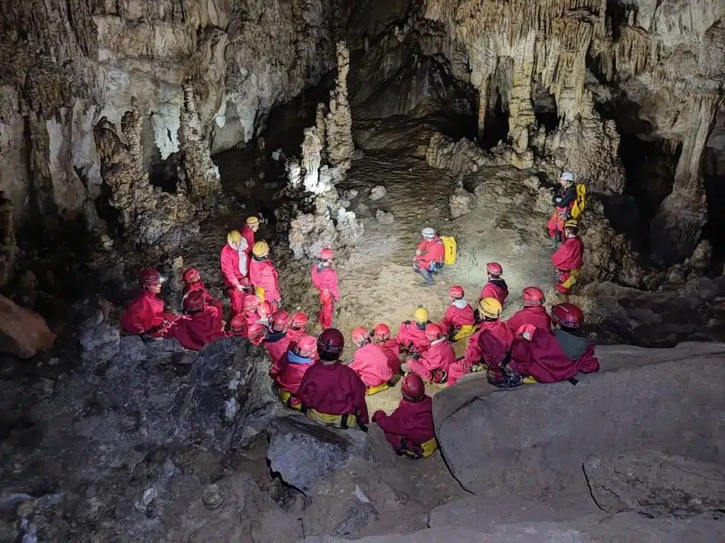 Grupo con casco y frontal entrando a una cueva guiado por VALCAN en el valle del Alto Asón