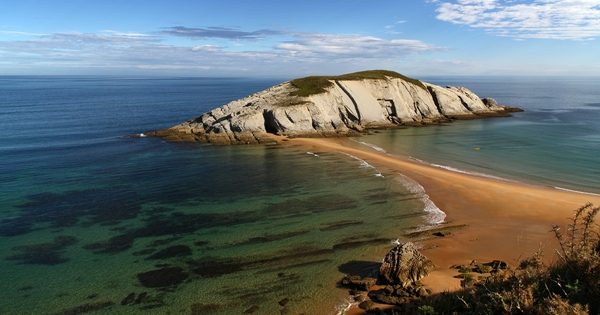 Blick auf den Strand Covachos und sein Eiland mit Kapelle, die Ebbe legt den Übergang frei.