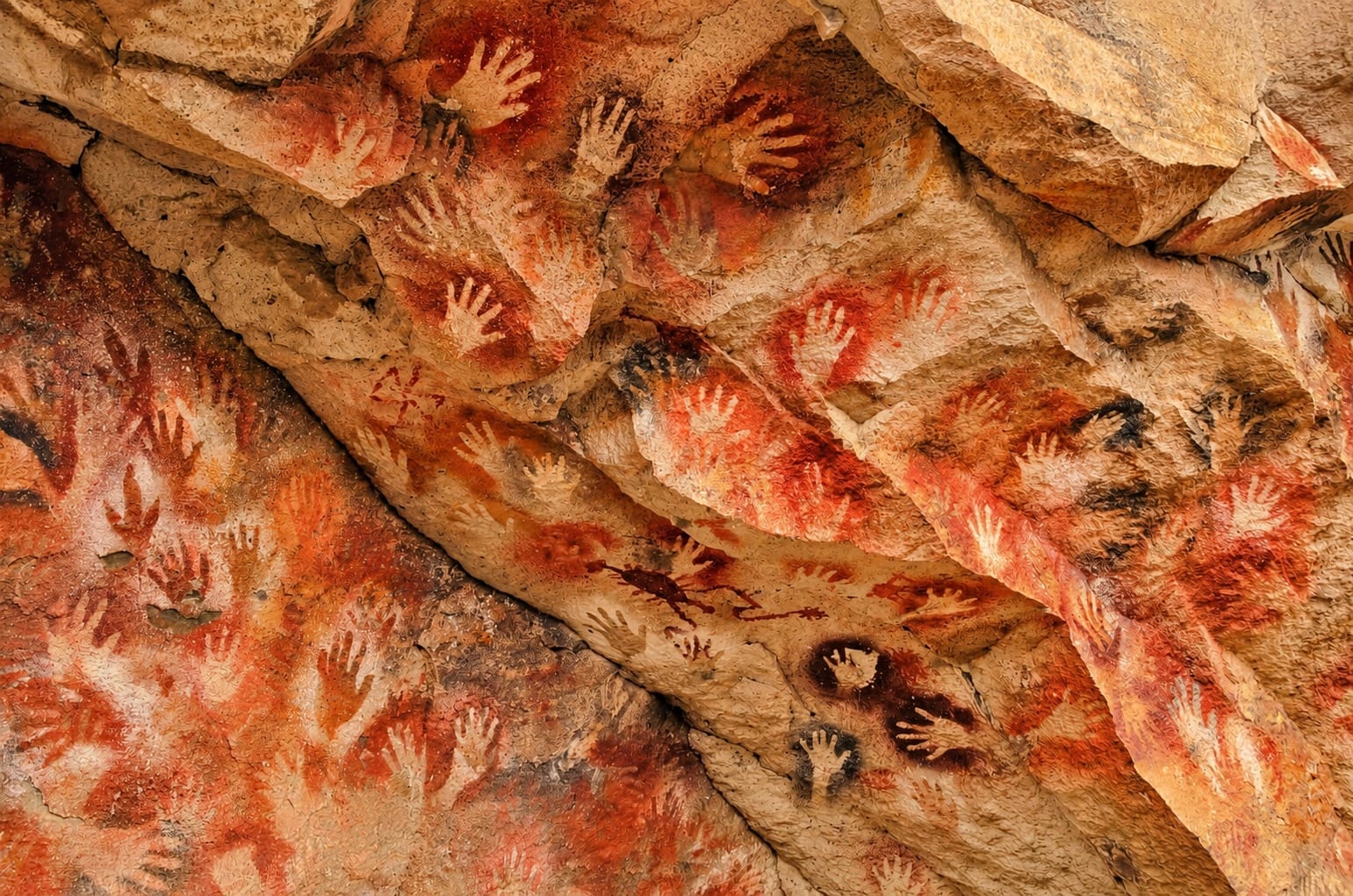 Siluetas de manos en rojo en el techo de una cueva paleolítica (detalle del arte rupestre de El Castillo)