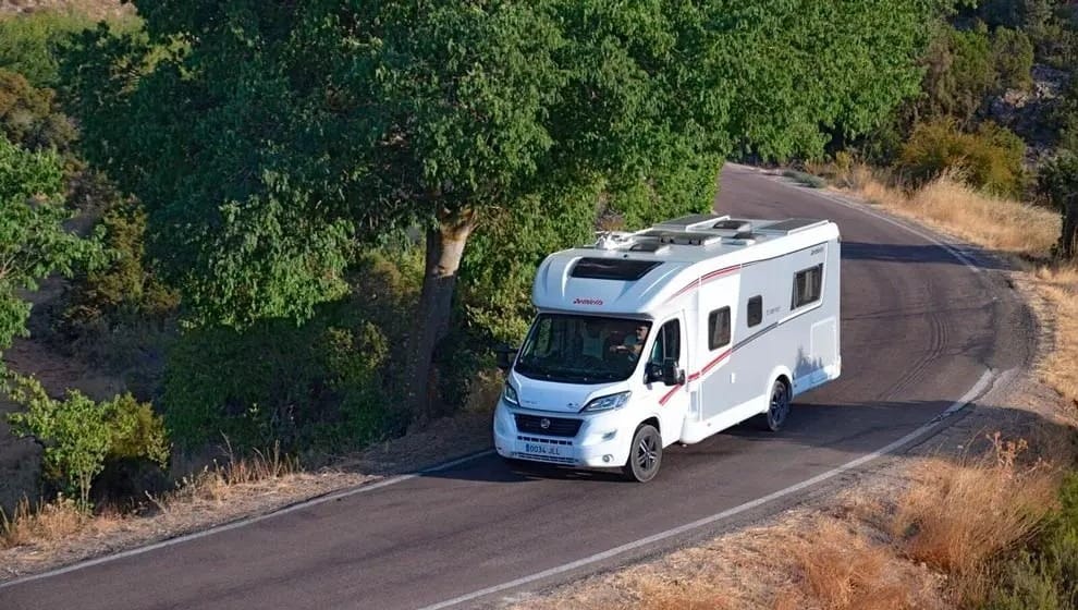 Autocaravana circulando por una carretera costera de la Trasmiera cántabra, mar al fondo.