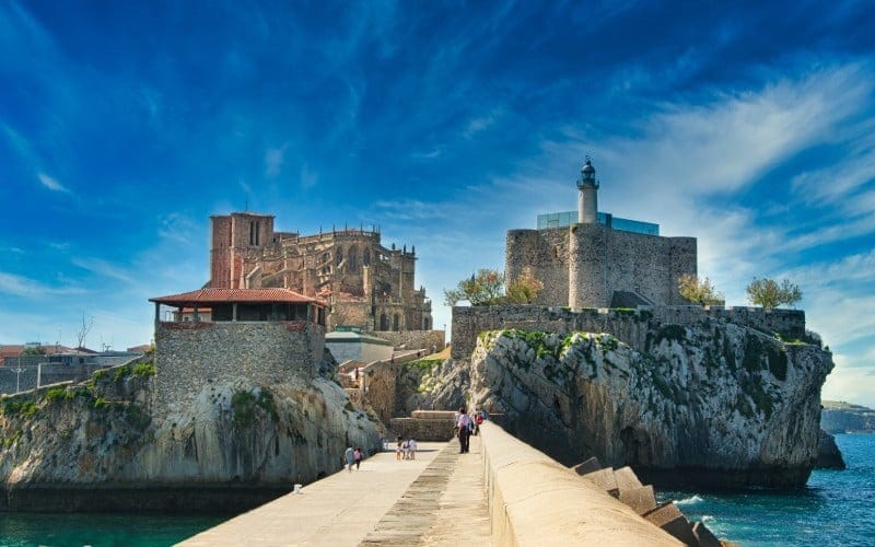 Vista general del conjunto monumental de Castro Urdiales desde el mar, con la iglesia de Santa María y el castillo-faro sobre el promontorio, luz de mañana