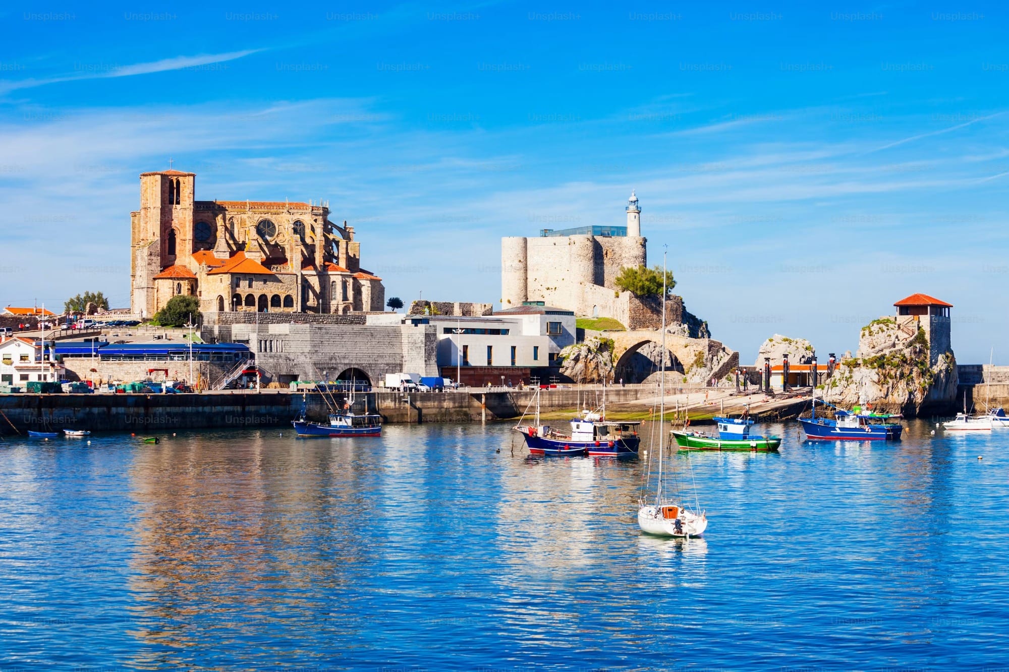 Puerto pesquero de Castro Urdiales al atardecer con las barcas amarradas y las marisquerías del paseo al fondo