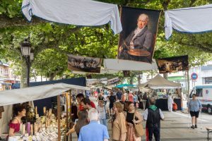 Kunsthandwerksstand mit Leder- und Keramikprodukten auf dem Napoleonischen Markt von Torrelavega, Menschen schlendern zwischen den Ständen