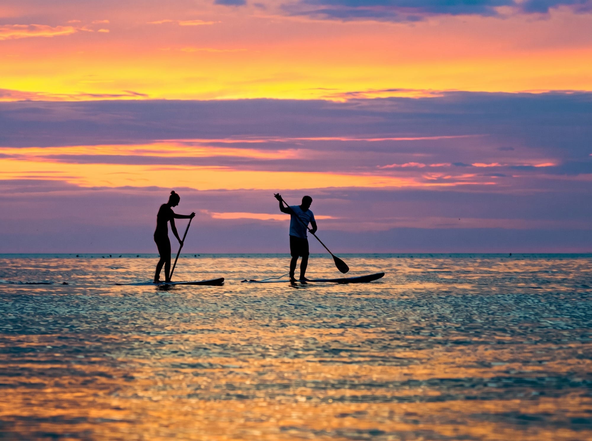 Paddle surf y surfistas con tabla en el agua frente a la playa de Cuchía
