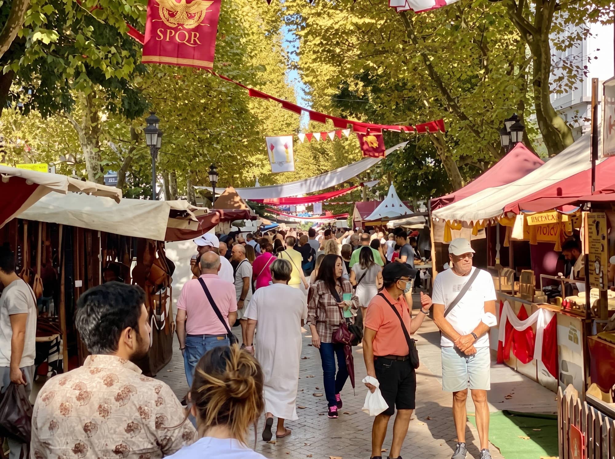 Puestos del mercado artesanal y agroalimentario en una calle del casco histórico, con gente comprando