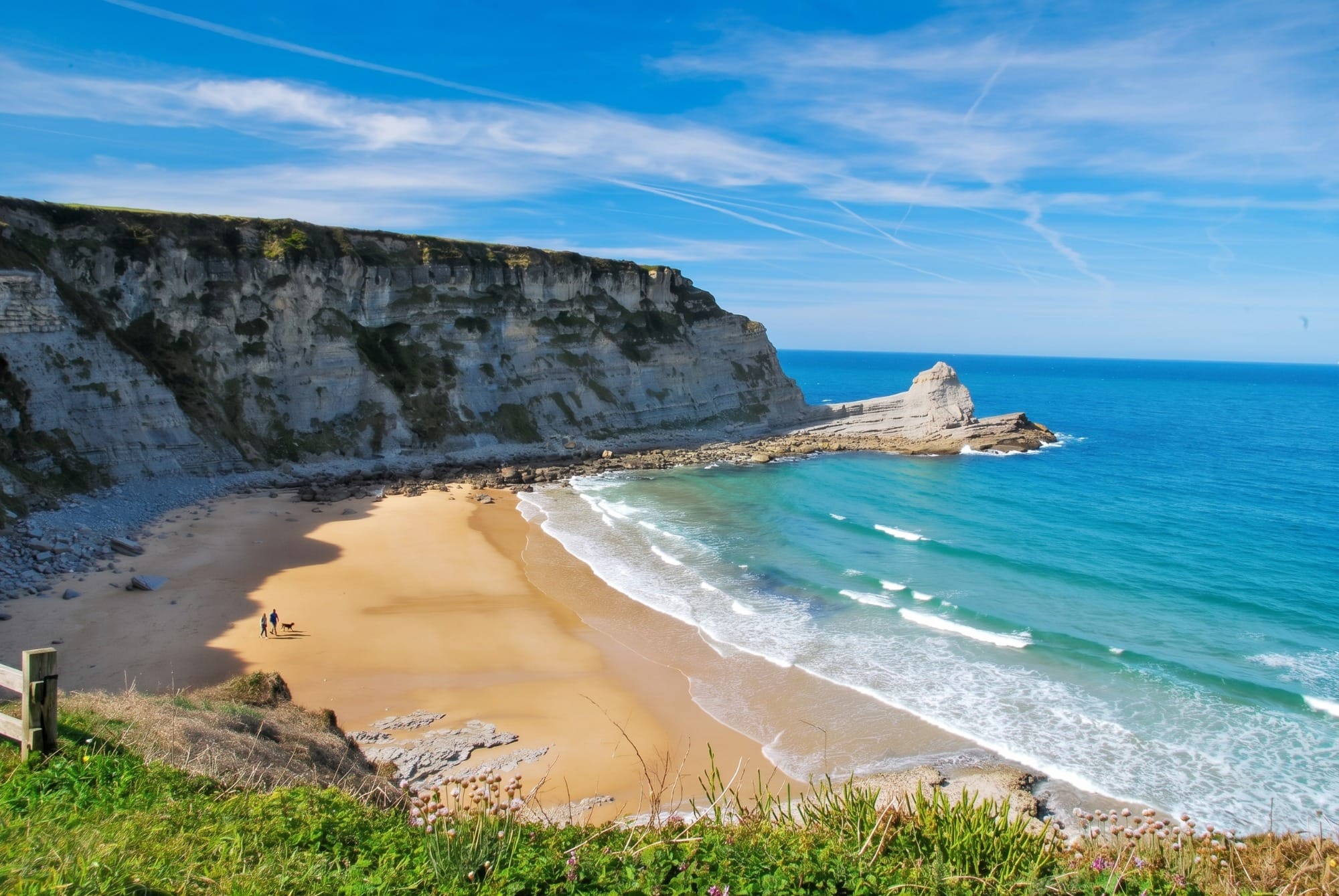 Playa de la costa oriental de Cantabria a media mañana de un día de junio, con poca gente y mar en calma