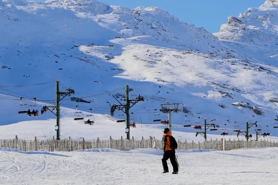 Pistas de Alto Campoo cubiertas de nieve con esquiadores y la montaña al fondo
