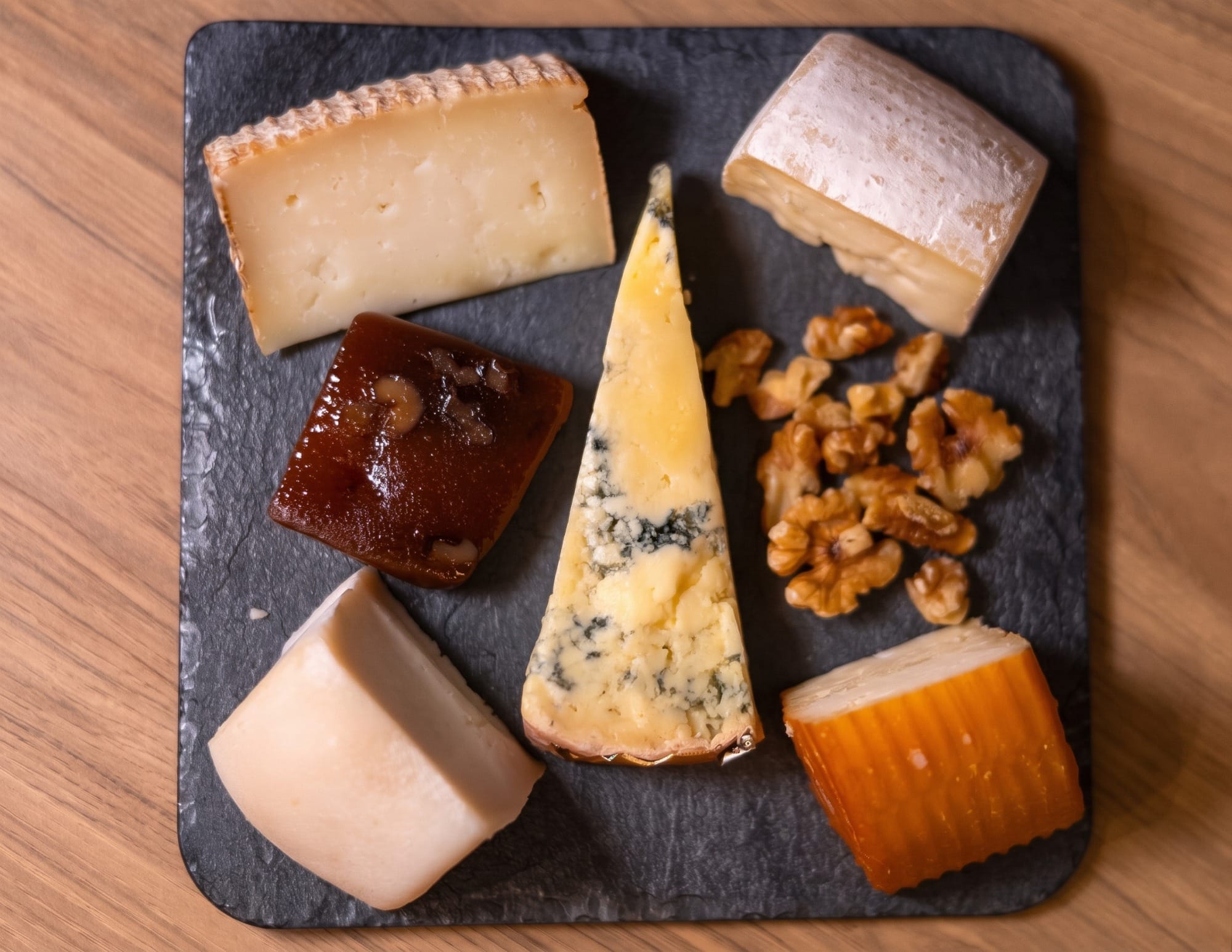 Tabla de quesos cántabros con quesuco, nata y picón sobre madera