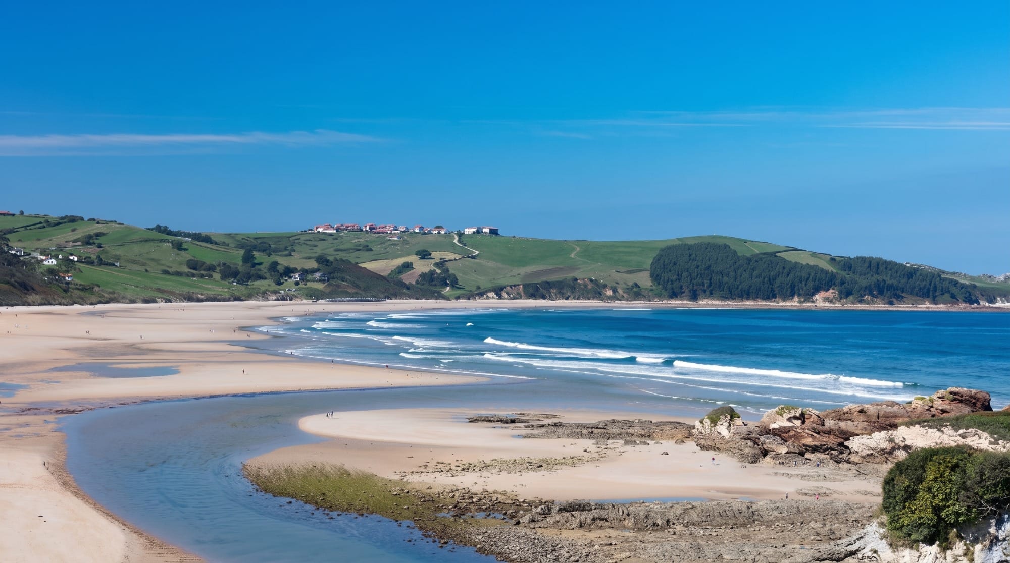 Oyambre beach with dunes and meadows behind, general view at low tide
