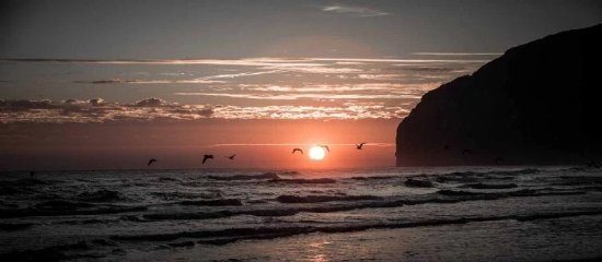 Playa de Berria en Santoña al atardecer, marea baja, siluetas paseando por la arena con Monte Buciero al fondo