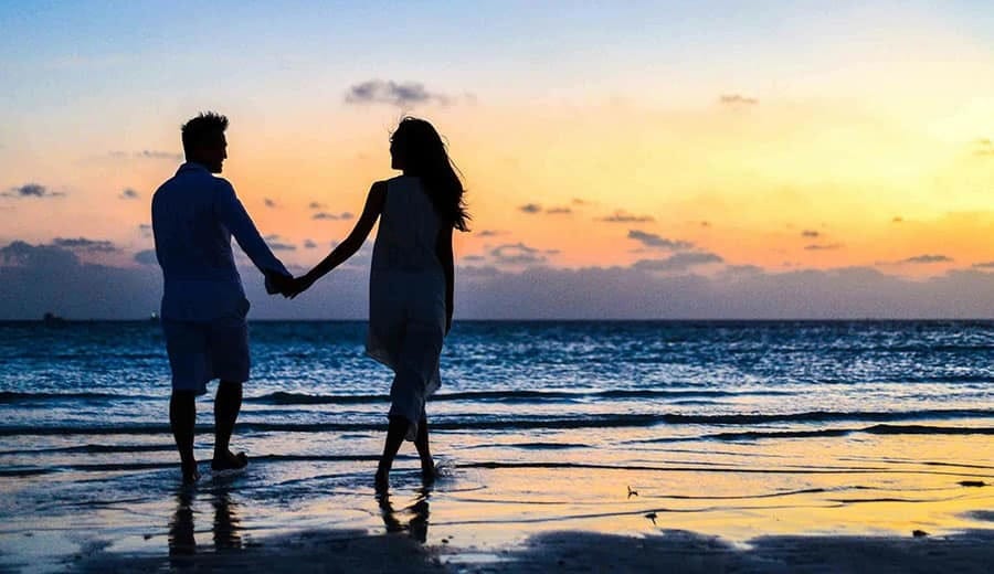 Paar beim Spaziergang an einem leeren kantabrischen Strand bei Sonnenuntergang im Winter