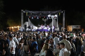 Ambiance de bal populaire de village la nuit, lumières de fête foraine et gens dansant sur une place cantabrique