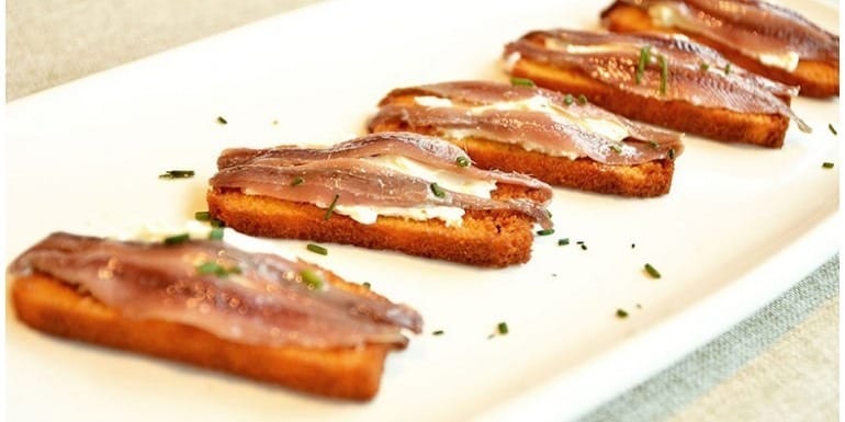 Tapa de anchoas de Santoña con pan y mantequilla sobre la barra de un bar