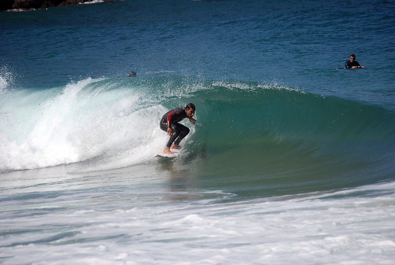 Surfistas principiantes con tabla entrando al agua en la playa de Cuberris (playa de Ajo), Bareyo, día soleado