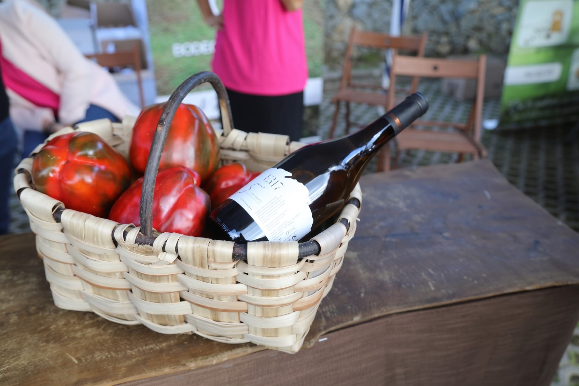 Pimientos de Isla recién recogidos en una cesta, con la huerta de Trasmiera al fondo