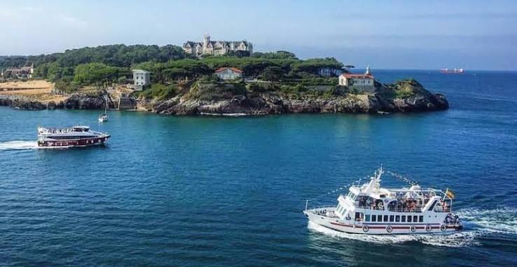 Baie de Santander avec des embarcations et le Palacete del Embarcadero en arrière-plan, matin dégagé.