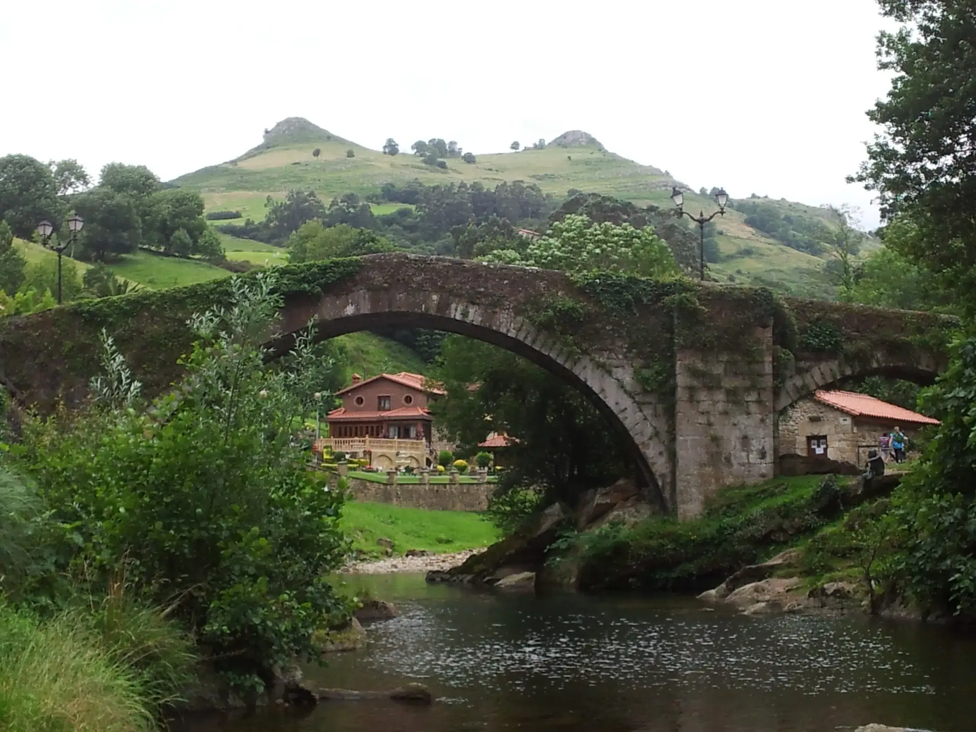 Course of the Miera river near Liérganes after a day of rain, visibly higher flow among green meadows, overcast sky.