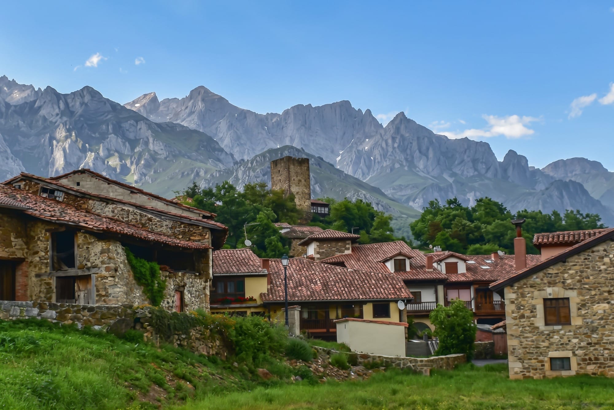 Stone and wood houses and medieval tower of Mogrovejo with the Picos de Europa behind