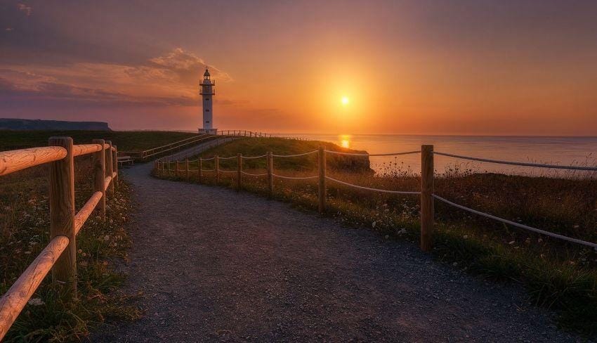 Atardecer sobre la costa de Cabo de Ajo, luz cálida, silueta del faro.