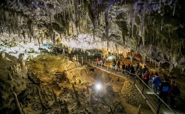 Interior de una cueva cántabra iluminada durante una visita guiada